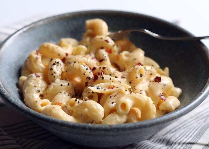 bowl of mac and cheese with black pepper and crushed red pepper